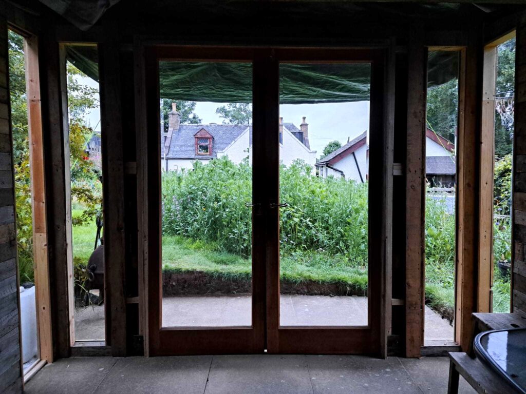 Inside view of repurposed wooden pallet summer house, looking out onto the garden.