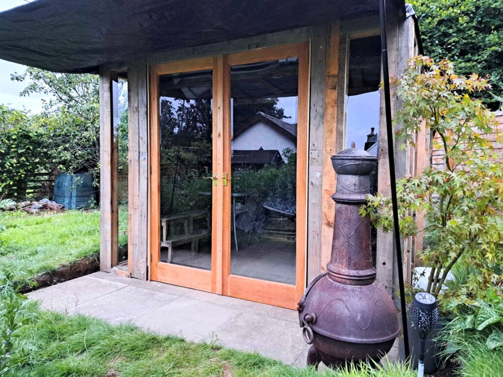 Front door view of repurposed wooden pallet summer house in garden.